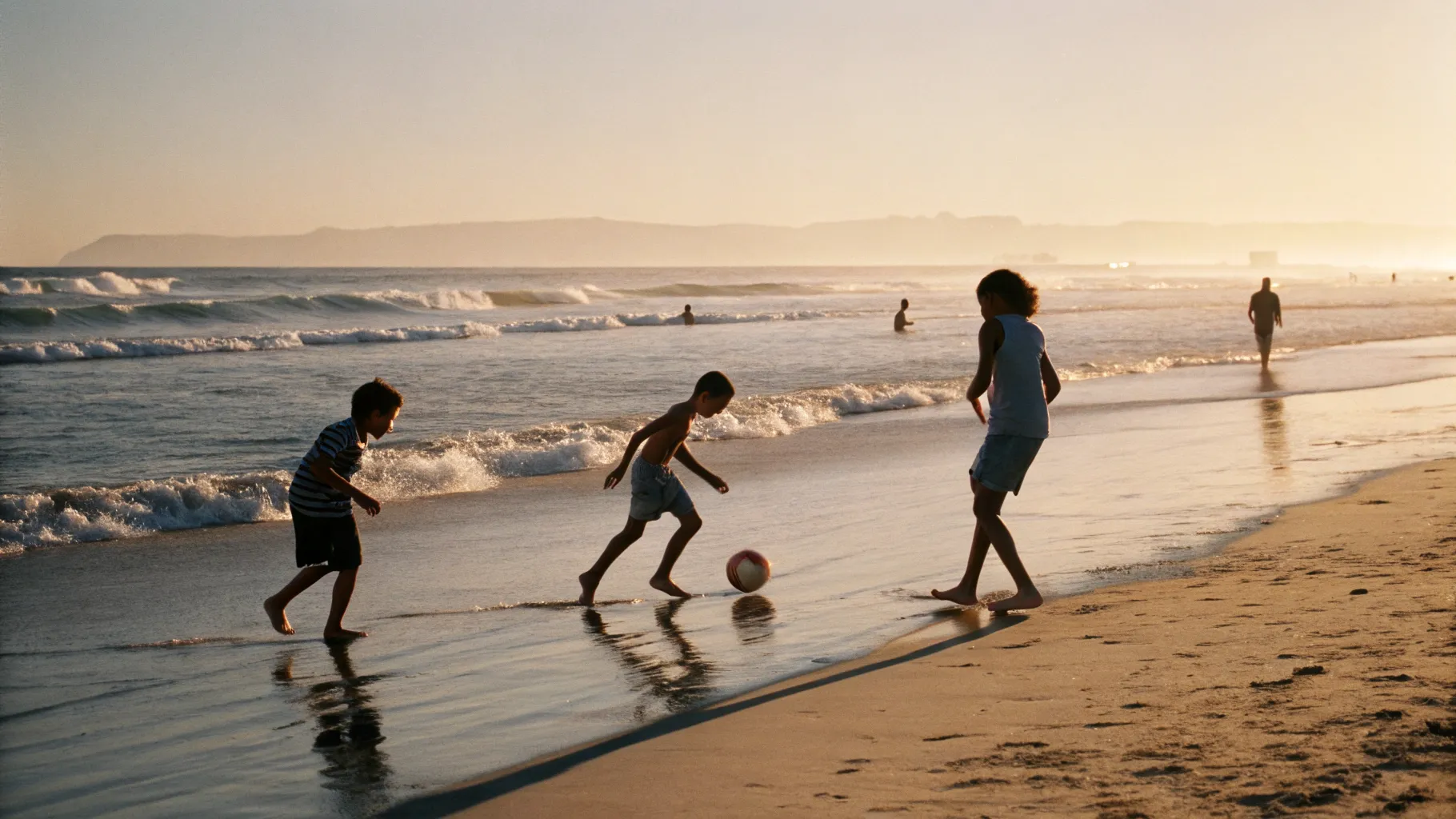 Children playing ball on the golden beach in the late afternoon sun